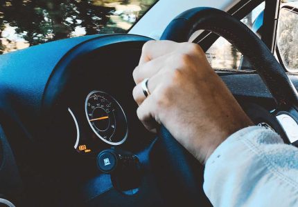 Left hand firmly grasping a steering wheel